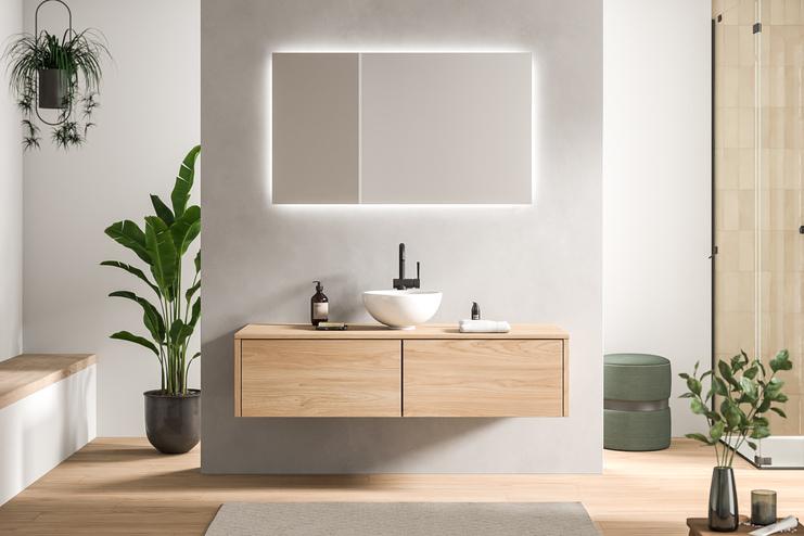 Geschmackvoll gestaltetes Bad nach Maß mit einem hellen Holzwaschtisch und einem rechteckigen, beleuchteten Spiegel, umgeben von Pflanzen.